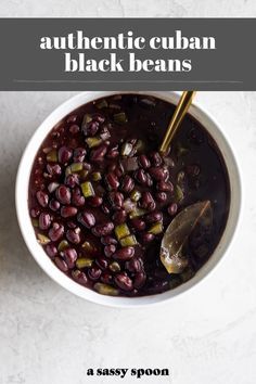 a white bowl filled with black beans next to a spoon on top of a table