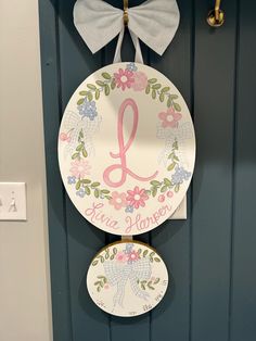 a door hanger with a monogrammed letter on it and a bow hanging from the front