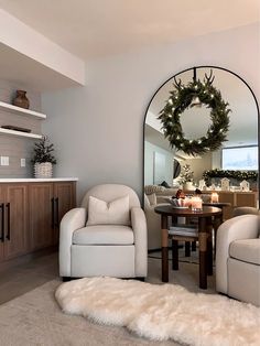 a living room filled with furniture and a large mirror over the fireplace covered in christmas wreaths