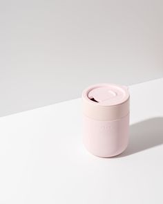 a pink cup sitting on top of a white table