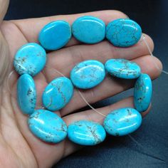 a person holding several turquoise stones in their hand and threading them to make it look like they are made out of stone