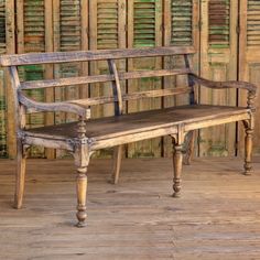 an old wooden bench sitting on top of a hard wood floor next to shutters