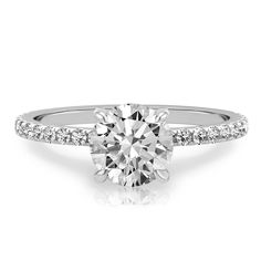 a white gold engagement ring with diamonds on the band and a round cut diamond in the center