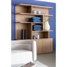 a white couch sitting in front of a wooden shelf filled with blue and white items