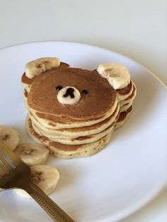 a stack of pancakes topped with banana slices and a teddy bear face