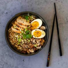 a bowl of ramen with noodles, mushrooms and hard boiled eggs on the side next to chopsticks