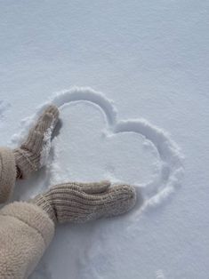 a teddy bear laying in the snow with a heart drawn on it