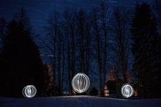 three light orbs in the snow at night with trees and stars behind them on a dark sky background