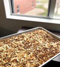 a pan filled with granola sitting on top of a table next to a window