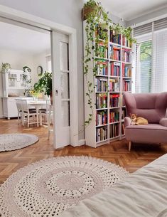 a living room filled with furniture and a book shelf full of books next to a window