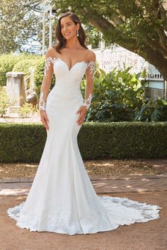 a woman in a wedding dress posing for the camera with her hands on her hips