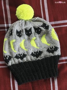 a knitted hat with black and yellow stars on it sitting on a red blanket