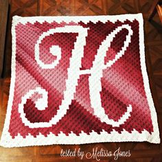 a red and white crocheted afghan with the letter p on it