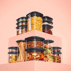 a stack of containers filled with food on top of a pink wall next to a pile of fries