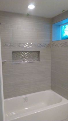 a white bath tub sitting inside of a bathroom next to a shower head and window