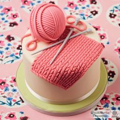 a cake with pink icing and yarn on top