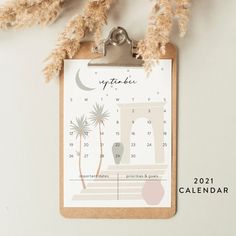 a clipboard with a calendar hanging from it's side next to dried plants