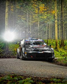 a car driving down a road in the woods at night with its headlights turned on