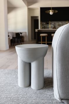 a white table sitting on top of a wooden floor next to a gray couch in a living room