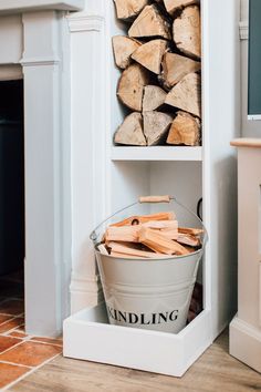 a bucket filled with wood next to a fireplace