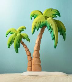 two paper palm trees sitting on top of a wooden table next to a blue wall