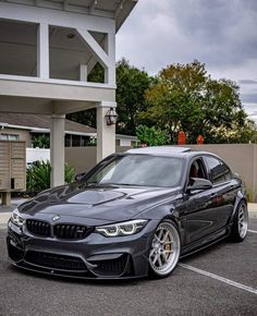 a grey car parked in front of a building with white trim and chrome rims