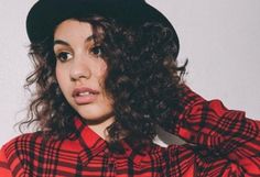 a woman with curly hair wearing a red and black plaid shirt