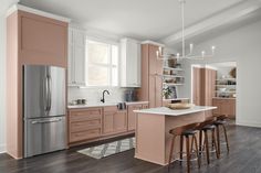 a kitchen with pink cabinets and white counter tops, an island in the middle is surrounded by bar stools