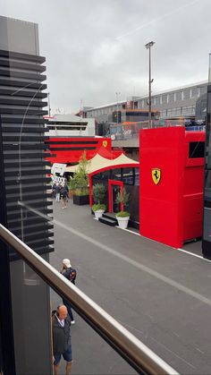 two people are standing on the balcony looking out at some sort of outdoor area that looks like a ferrari store