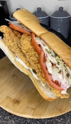 a chicken sandwich with lettuce and tomato on a cutting board in the kitchen