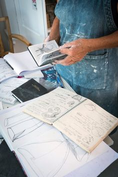 a man standing in front of a table with drawings and papers on top of it