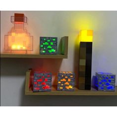 several lit up cubes are sitting on the shelf next to each other in front of a candle