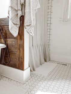 a bathroom with a sink, toilet and shower curtained in white lace on the curtains