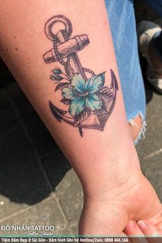 an anchor tattoo on the arm of a person with a flower in its center,