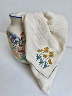 two white vases with embroidered designs on them