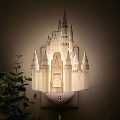 a castle shaped night light on a wall next to a potted plant with green leaves