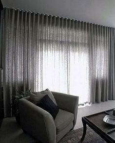 a living room filled with furniture and a window covered in sheer draping next to a coffee table