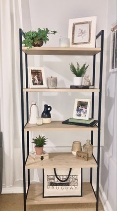 a book shelf with pictures and plants on it