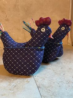 two blue chickens with red bows on their heads are sitting in front of a wall