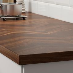 a wooden counter top in a kitchen with white tile backsplash and dark wood grain