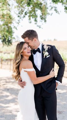 a bride and groom hugging each other in front of a tree