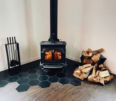 a wood burning stove in a room next to stacks of firewood on the floor