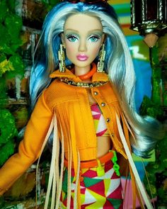 a barbie doll with blue hair wearing an orange jacket and multicolored skirt in front of a green background