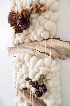 two pieces of driftwood are hanging on the wall with cotton balls and acorns