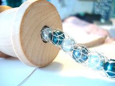 a wooden spool with some glass beads on it's end sitting on a table