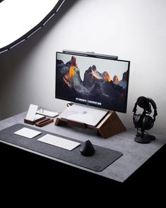 a computer monitor sitting on top of a desk next to a mouse and headphones