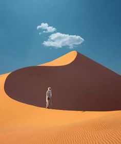 a person standing in the middle of a desert with a cloud in the sky above