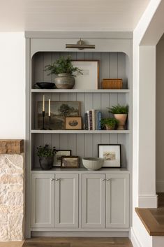 a book shelf with books, plants and pictures on it