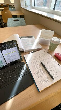 an open notebook and pen sitting on top of a table next to a laptop computer