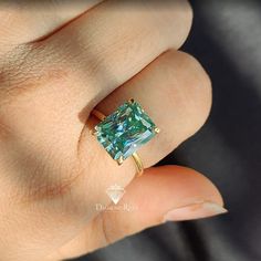 a woman's hand with a ring that has a blue and green stone in it